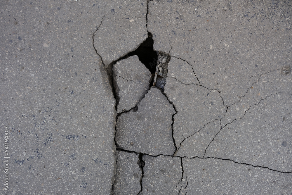 Road surface with cracks and pits, closeup. Bridge is in an emergency