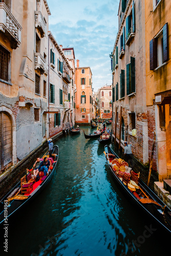 Typical Venetian canal crowded with gondolas crossing it