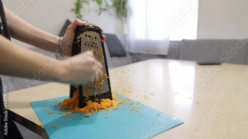 rubs carrots on a grater for cooking