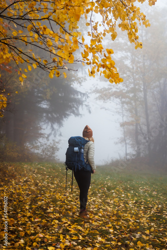 Hiking in autumn forest. Woman with backpack trekking in foggy nature © encierro