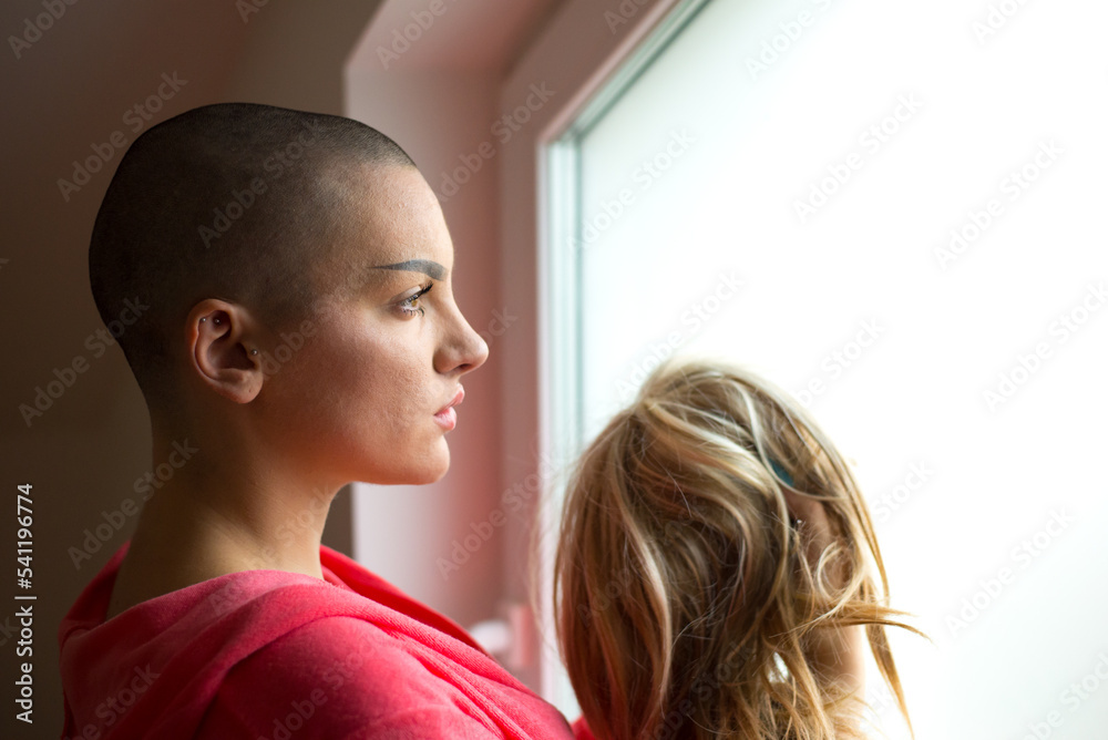Young depressed female cancer patient standing in hospital beside window Young depressed female cancer patient standing in hospital beside window
