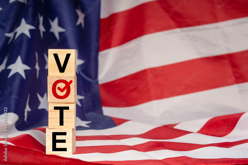 Obraz premium Side view of wooden cubes with letters VOTE on the American flag background