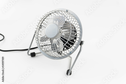 Mini electric fan for table side view. Silver color. White background.