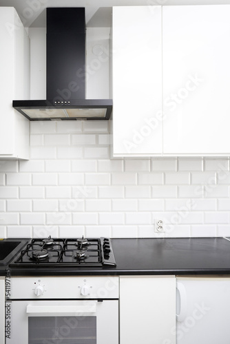 Small  kitchen design with white kitchen cabinets, white kitchen island with lots of storage, black countertops, subway tiles, gas stove.