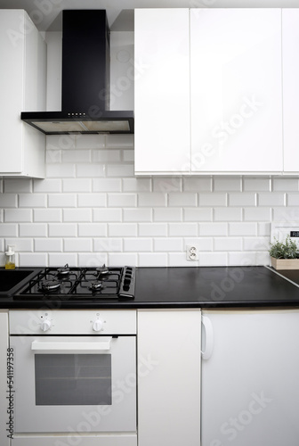 Small  kitchen design with white kitchen cabinets, white kitchen island with lots of storage, black countertops, subway tiles, gas stove.
