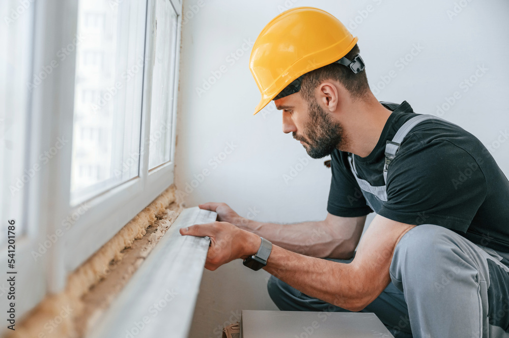 Installing a window sill. The man is making repairs in the apartment Installing a window sill. The man is making repairs in the apartment