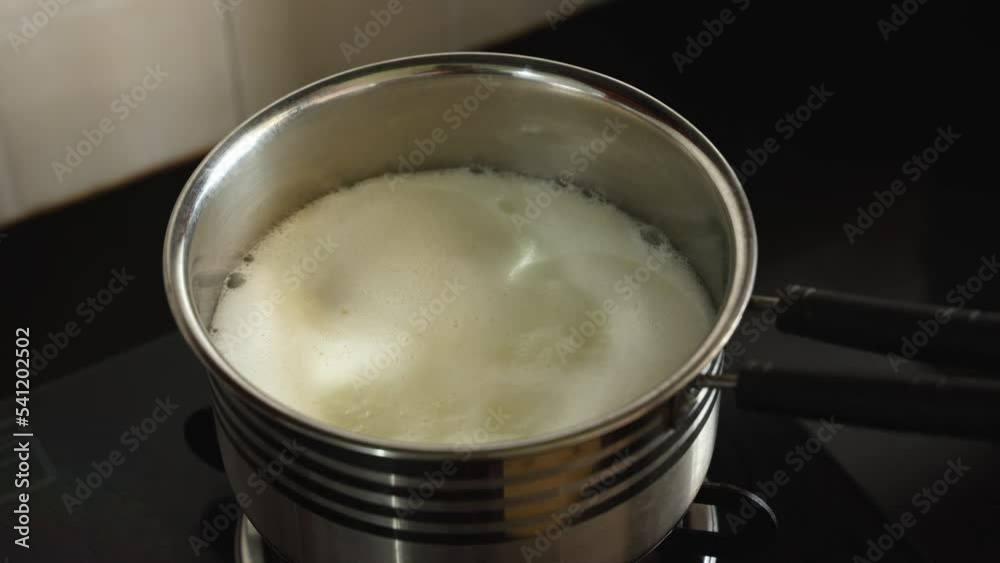 Video „Boiling milk on gas stove, White thick layer of form over milk