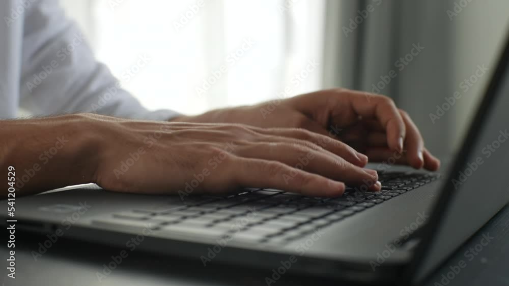 Close-up cropped shot of unrecognizable business man typing on laptop keyboard working at office desk on background of window. Male freelancer busy with business activity at remote home office. Close-up cropped shot of unrecognizable business man typing on laptop keyboard working at office desk on background of window. Male freelancer busy with business activity at remote home office.