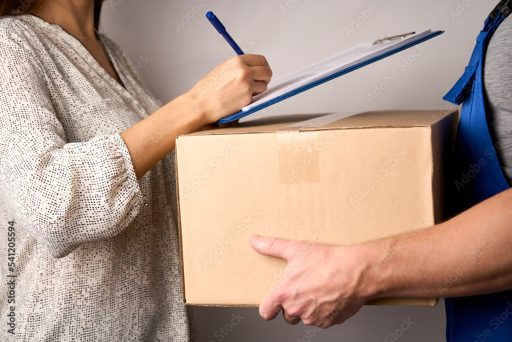 Delivery man giving cardboard box to female hand Delivery man giving cardboard box to female hand