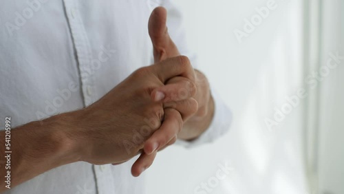 Close-up cropped shot of unrecognizable stressed man racking knuckles and fingers feeling nervous on white background. Male rubbing sore painful hand, fingers and knuckles. Shooting in slow motion.