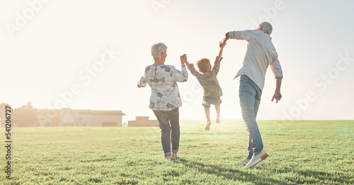 Love, grandparents and child being playful, happy and bonding on grass, outdoor and together. Grandmother, grandfather and kid enjoy summer holidays, adventure or travel for walking or holding hands photo