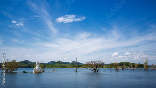 Long expousre of statue of Buddha in the middle of the water at the with at morning light abandoned temple at Khao Rakam Reservoir, Trat Province, Thailand