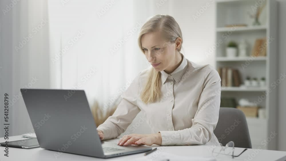 Experienced female freelancer working on laptop from home, sitting at desk Experienced female freelancer working on laptop from home, sitting at desk