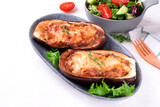Stuffed eggplant halves with roasted vegetables, champignons and cheese served on the gray plate. Hot vegetarian meal
