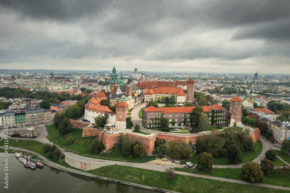 Aerial view of the Wawel hill, with the Royal Wawel Castle, towers and cathedral, Vistula river, background - Old Town on left, Cracow city. Krakow, Poland, September 2022. Cloudy day.
