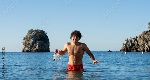 young man with snorkeling mask in his hand struggling to enter the cold sea on vacation