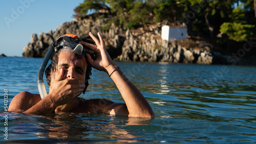 Young boy taking off his diving mask and wipes the water from his face.