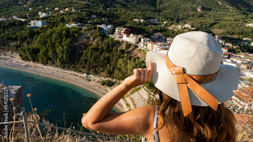 Young woman with hat looking in the direction of the Valtos beach in Parga,  Greece. Vacation, travel, summertime concept.