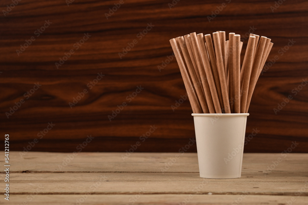 Paper Straws in a Paper Cup on Wooden Table - obrazy, fototapety, plakaty 