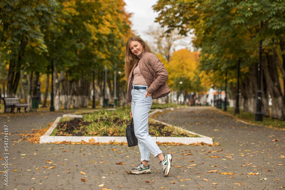 Fototapeta premium Happy beautiful red-haired woman posing in autumn park