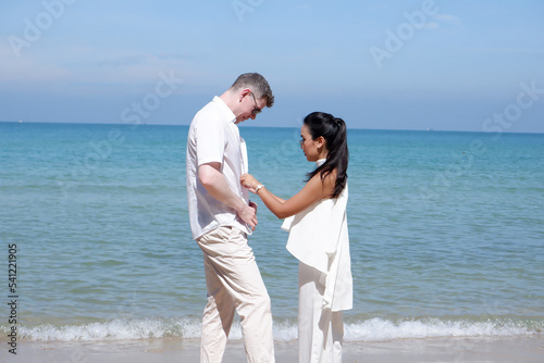 Male and female couple standing at the beach.