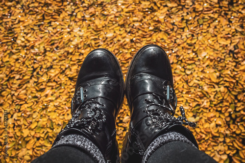 Black boots dangling above a sea of golden leaves