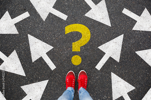 woman in red sneakers standing on asphalt next to multitude of arrows in different directions and question mark, confusion choice chaos concept