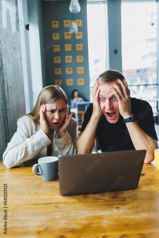 Young colleagues managers are sitting at the table and laughing. Concept of business cooperation and teamwork. Young smiling people at the table in the office with a laptop. Modern successful people
