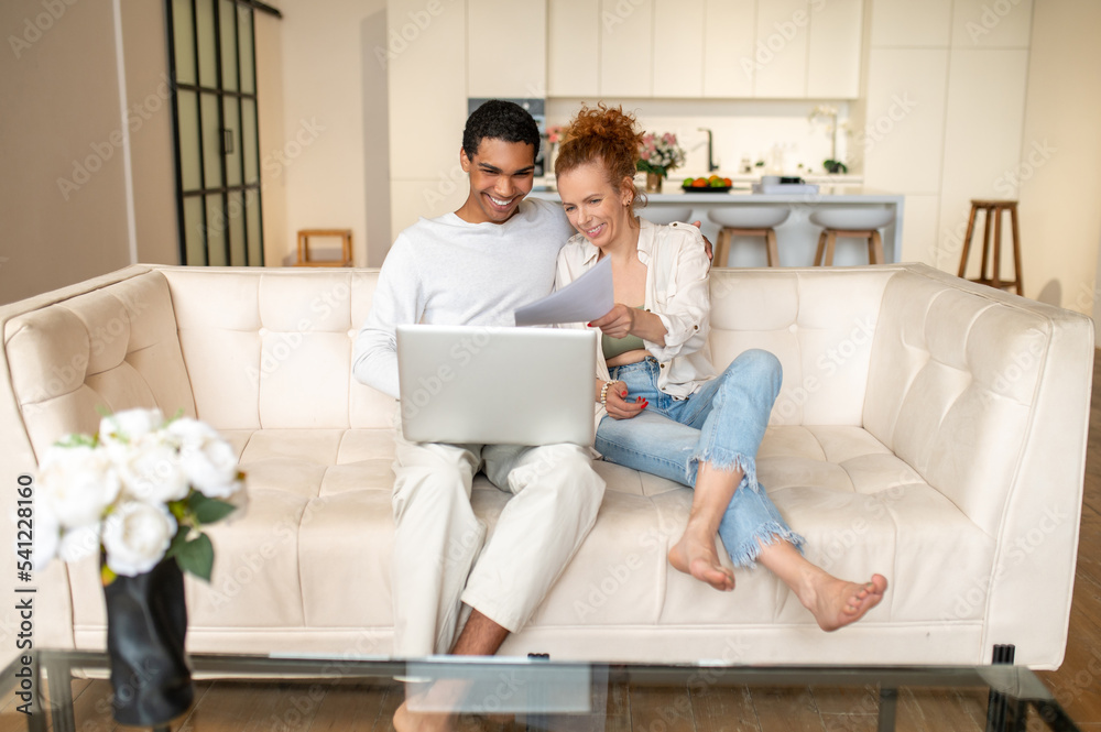 Two young people sitting on the sofa and choosing something online Two young people sitting on the sofa and choosing something online