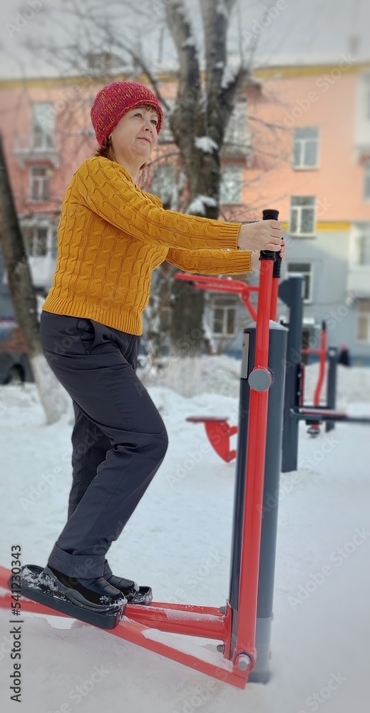 A woman on a simulator in winter performs exercises to strengthen muscles.The concept of a healthy lifestyle. A woman on a simulator in winter performs exercises to strengthen muscles.The concept of a healthy lifestyle.