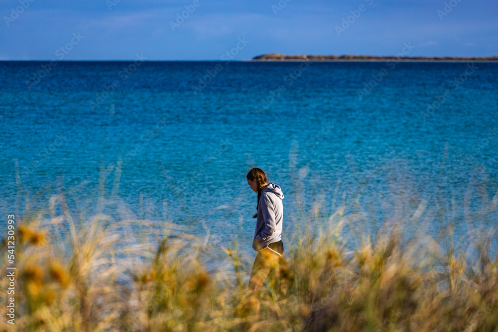 sweet girl in pigtails walks on coral bay beach at sunrise; warm morning on famous paradise beach in western australia, at ningaloo reef