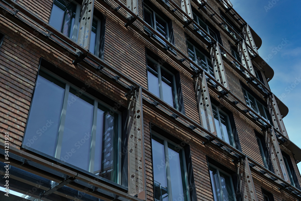 Exterior of modern red brick house with metal inserts. Architectural detail of close-up on windows. Real estate, residential apartments and offices. Living apartments or office building architecture. Exterior of modern red brick house with metal inserts. Architectural detail of close-up on windows. Real estate, residential apartments and offices. Living apartments or office building architecture.