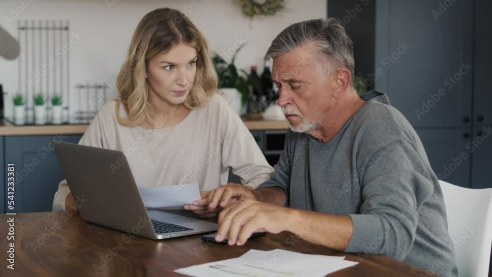 Caucasian senior man and adult daughter counting home finance. Shot with RED helium camera in 8K. Caucasian senior man and adult daughter counting home finance. Shot with RED helium camera in 8K.