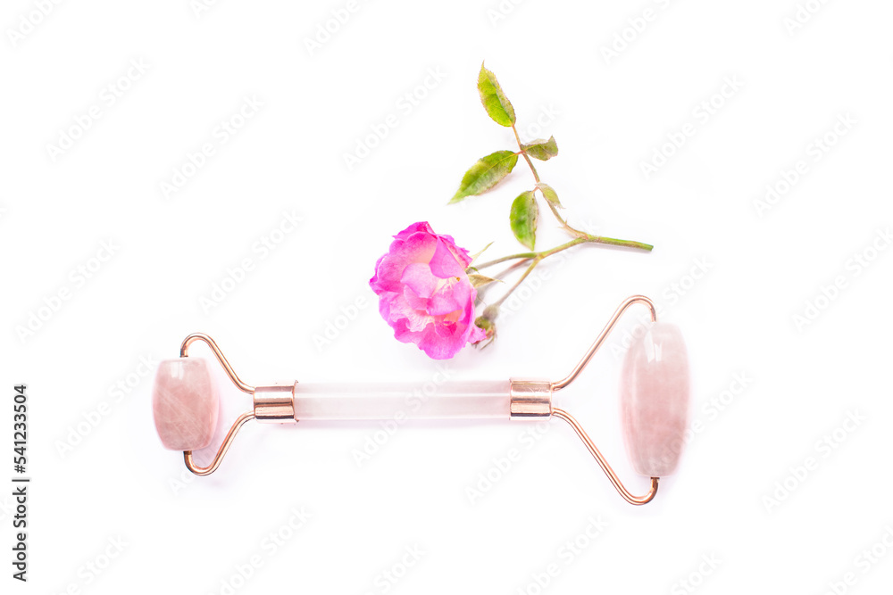 beauty and skin care concept, with a rose quartz facial massager accompanied by a pink flower