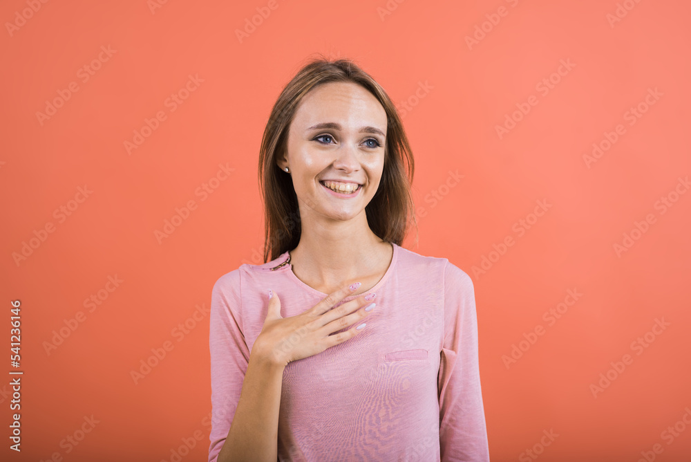 The girl holds her hand on her chest and laughs loudly at a anecdote on a red background. The girl holds her hand on her chest and laughs loudly at a anecdote on a red background.