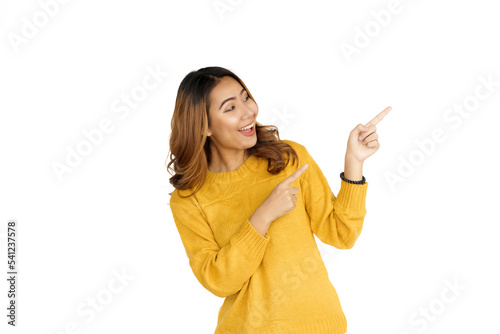 Attractive positive young asian brunette woman in yellow sweater on white background. Pointing and surprise