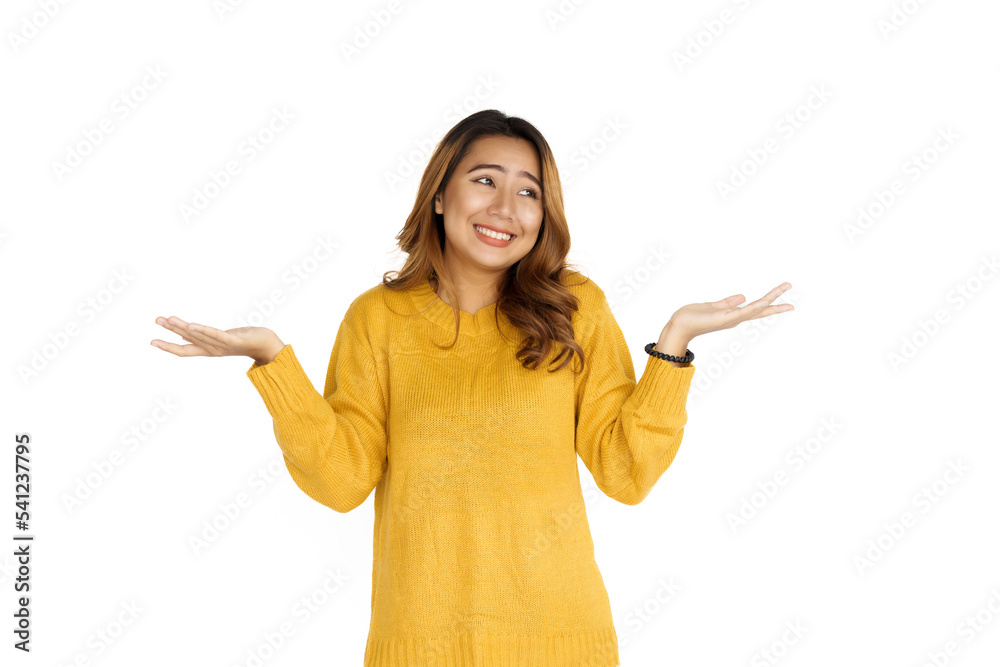 Attractive positive young asian brunette woman in yellow sweater on white background, palm up and surprise