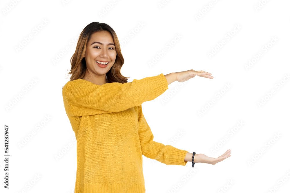 Attractive positive young asian brunette woman in yellow sweater on white background, hands holding something Attractive positive young asian brunette woman in yellow sweater on white background, hands holding something
