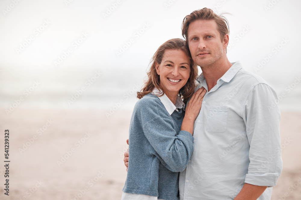 Happy, couple and portrait smile on a beach together relaxing while enjoying quality bonding time in the outdoors. Man and woman smiling in happiness for hug, relationship love or care on sandy ocean Happy, couple and portrait smile on a beach together relaxing while enjoying quality bonding time in the outdoors. Man and woman smiling in happiness for hug, relationship love or care on sandy ocean