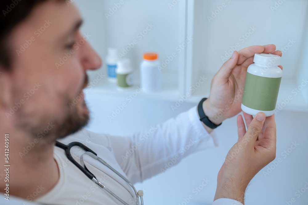 Doctor reading the label on a dietary supplement Doctor reading the label on a dietary supplement