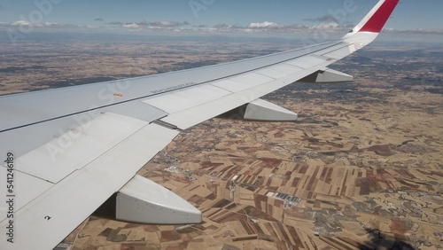 Madrid 2022 - Iberia AIRLINES flying by plane - view from the window porthole of the wing plane during the flight with a view of the land below arid and cultivated in Spain Madrid