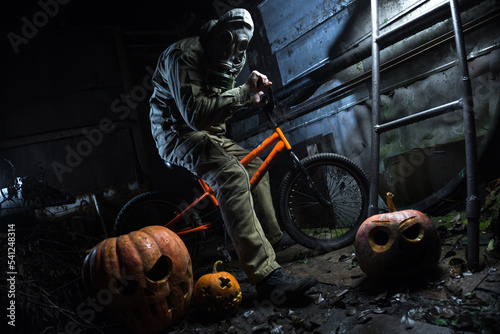 a man in a gas mask with orange halloween pumpkins celebrates the holiday © yurii oliinyk