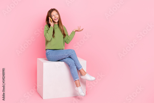 Full length photo of dreamy funny schoolgirl wear sweatshirt communicating modern gadget looking empty space isolated pink color background