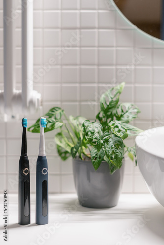 Two wireless sonic toothbrush near basin in bathroom photo