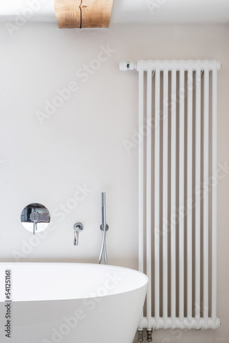 Central heating in bathroom near white modern tub