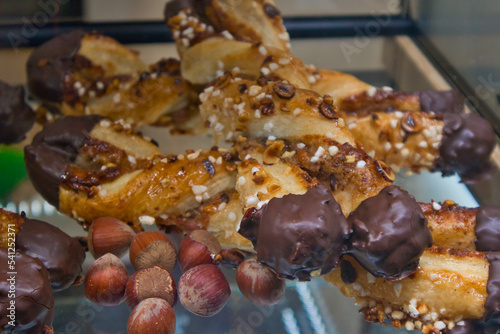 Sweet twisted puff pastry with crystal sugar and almonds. Chocolate-coated puff pastry with hazelnuts. Sweet pastry on a display in a bakery shop. Tasty baked sweet desert with almonds and chocolate. 