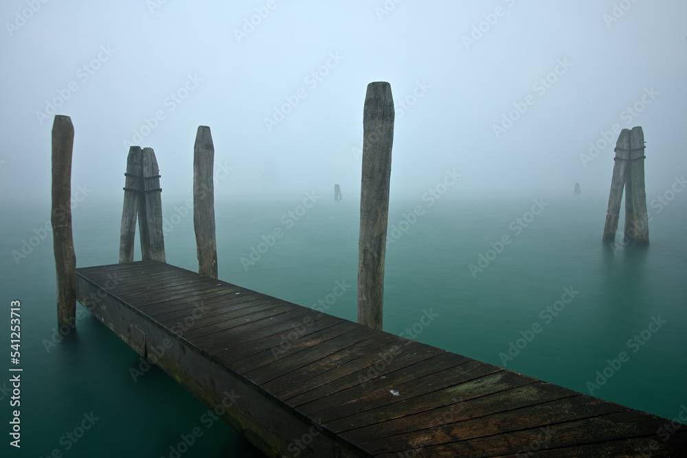 Ein Bootssteg am Meer bei starkem Nebel.