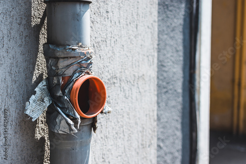 Rain gutter repaired or patched with duck tape. Adhesive tape applied at a drainage pipe spout