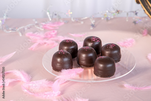 Sponge marshmallow candy covered in chocolate and vanilla wafer underneath, on a pink background. photo