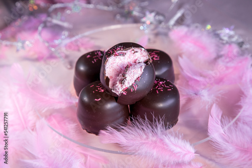 Sponge marshmallow candy covered in chocolate and vanilla wafer underneath, on a pink background. photo